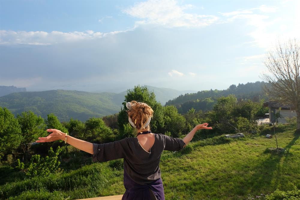 Caroline, de La Ferme Ouverte, de dos face aux montagnes des Pyrénées